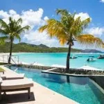 Palm trees beside a resort pool and a tropical beach